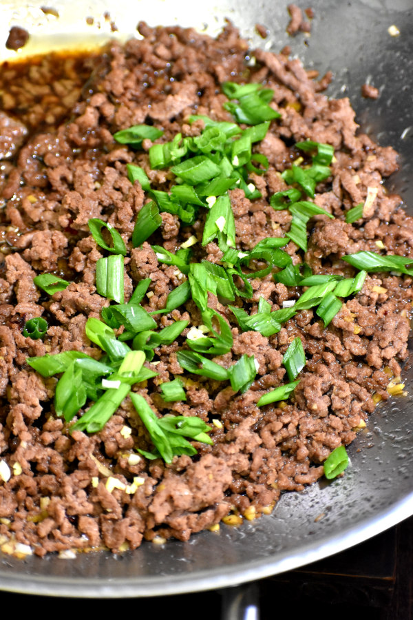 牛肉在锅里煎，加入大蒜和姜，葱花