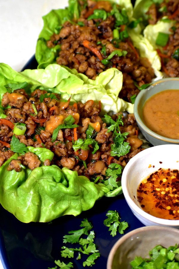 鸡肉生菜包裹在蓝色板与花生酱,大蒜辣椒酱和葱